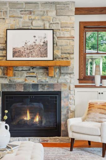 Bright and airy family room with gas fireplace, stone surround, wood mantle and built-in custom cabinetry.