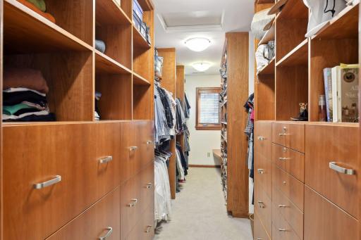 Primary walk in closet with custom cabinetry