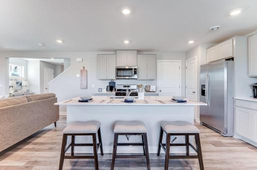 Enjoy a beautiful island with quartz countertops and barstool seating open to the dining room! (Model photo, colors may vary.)