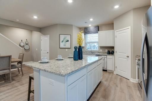 A kitchen built to perform - complete with an oversized island, corner pantry, stainless appliance package including a vented microwave, dishwasher and gas range, stone gray cabinets and quartz counters. Photos of model. Options and colors may vary.