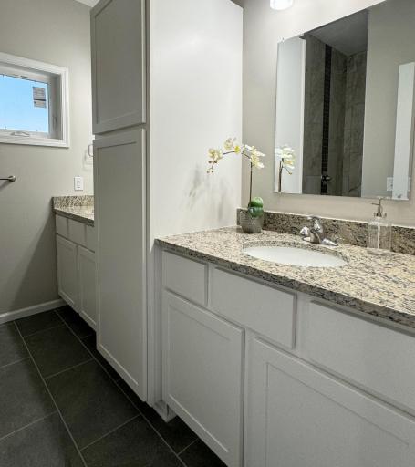 Double vanity with beautiful soft close cabinets, granite countertops, stunning walk-in tiled shower, and tiled floors.