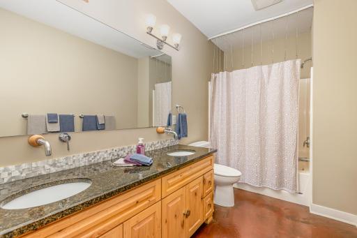 Lower level bathroom with dual sinks and a tub.