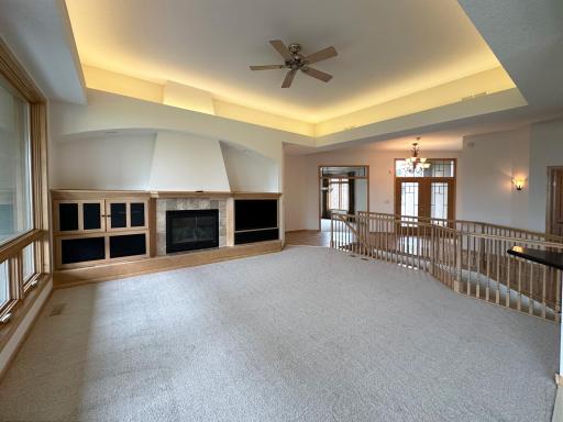 Open living room with gas fireplace, tray lights, tv and speaker connections.