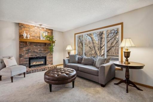 The beautiful living room features a lovely brick fireplace (with new electric insert), brand new neutral carpeting and new energy efficient windows.