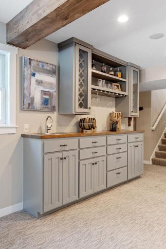 Enameled wet bar features built-in wine racks, stemware display, open shelving, roll-out storage and butcher block top w/ stainless steel sink