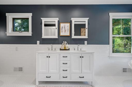Primary Bathroom features enameled vanity cabinet w/ marble top & dual undermount sinks, nostalgic hexagon ceramic flooring and classic subway tile wainscoting