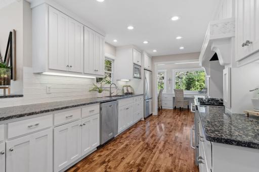 Custom enameled cabinetry featuring flat panel doors, open display shelvings, roll-outs, under cabinet lighting and an "Eat-In-" raised counter