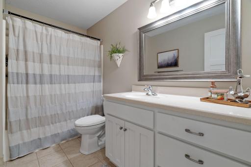 Full Bathroom on Main Level features ceramic flooring and enameled vanity & solid surface countertop w/ integrated sink