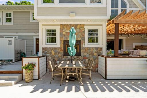 Lower level patio features a see-through gas fireplace w/ river rock surround & stone walls