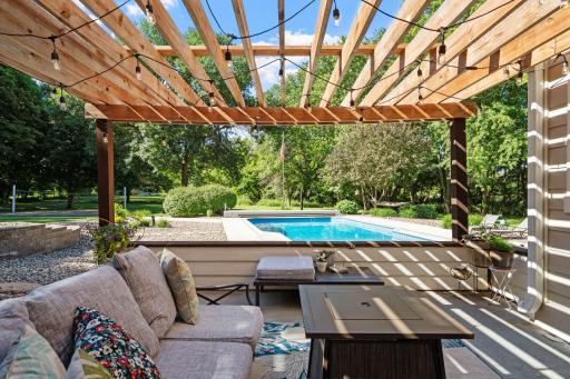 Lower level concrete patio boasts a pergola w/ patio lights