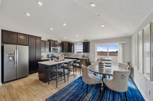 This stunning kitchen features a large center island, quartz countertops, LVP floors, stainless appliances and more! Actual homes cabinets will be white. (Photo of a decorated model, actual homes finishes will vary)
