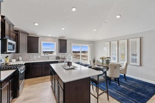 Enjoy plenty of seating at the kitchen island and dining area adjacent. Perfect for entertaining or having a family meal together. Actual homes cabinets will be white. (Photo of a decorated model, actual homes finishes will vary)