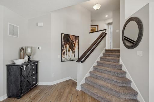 Accessibly located near the main entrance, this elegant staircase leads to the upper level. (Photo of a decorated model, actual homes finishes will vary)
