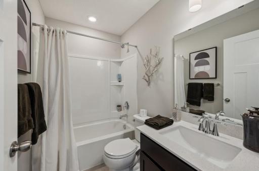 Upstairs hallway bath with luxury vinyl plank flooring and quartz countertops. Actual cabinet will be white. (Photo of a decorated model, actual homes finishes will vary)