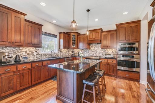 Gormet kitchen appointed with granite countertops, custom cherry cabinetry, enhanced back splash, stainless steal appliances, center island with breakfast bar - all atop the dynamic walnut hardwoods.
