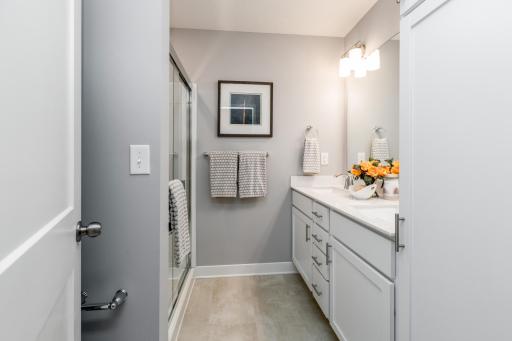 (Photo of decorated model, actual home's finishes may vary slightly) An extension of the owner's suite, this private and spacious bath contains a double-vanity and a shower.