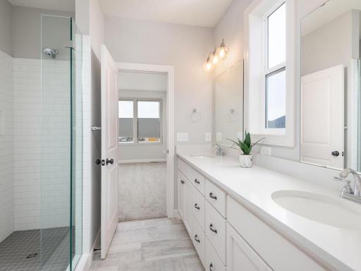 Primary private 3/4 Bath is complete with double-sink vanity & walk-in tiled shower stall.