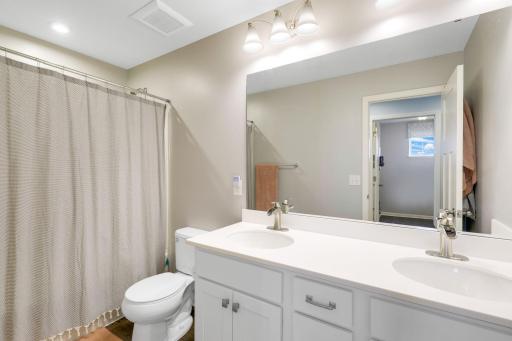 Secondary full bathroom on upper level with dual vanity and shower/tub combo.