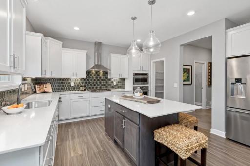The spacious gourmet kitchen includes a large center island, quartz countertops, LVP floors, stainless appliances and more!