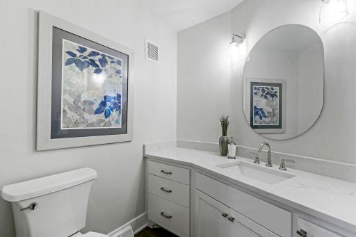 Powder Room offers large enameled vanity cabinet with quartz countertop & white oak engineered hardwood flooring