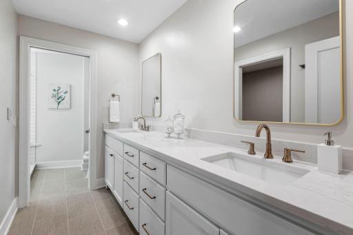 Enameled vanity cabinet w/ quartz countertop, dual sinks & modern tile floors w/ radiant in-floor heat