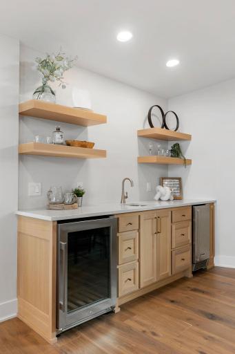 Built-in oak beverage center offers a beverage refrigerator, ice maker, storage and floating display shelves