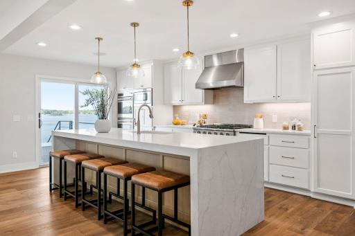 Custom enameled cabinetry features flat panel doors, open display shelving, full height pantry, roll-out storage, under cabinet lighting and large white oak "Eat-in" center island