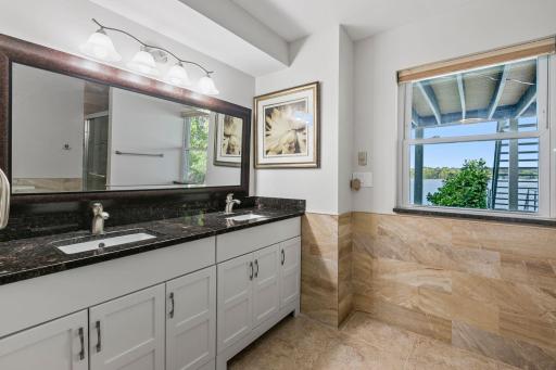 3/4 Bathroom offers enameled vanity cabinet w/ dual undermount sinks & granite countertop. Modern tile wainscoting and flooring w/ natural light!