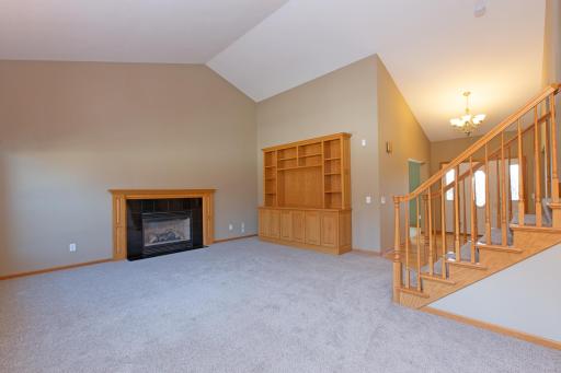 Large vaulted family room with built in cabinets, a cozy fireplace and brand new carpet.
