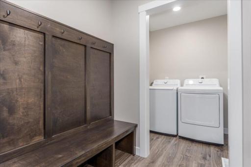Main level laundry room and custom built-in bench with hooks coming in from the garage.