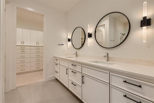 Dual vanity in primary suite with custom cabinets and built in closet system.