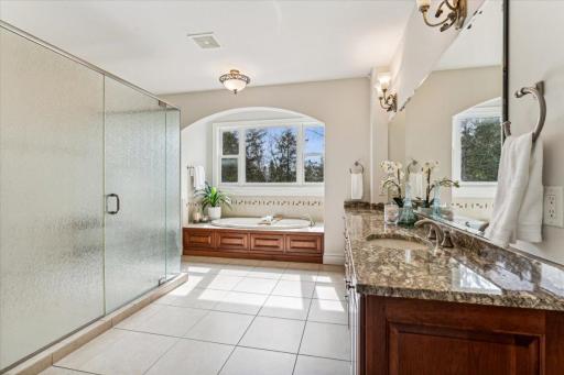 Gorgeous ensuite bath featuring heated tile flooring, large shower, dual sink vanity, and separate tub.