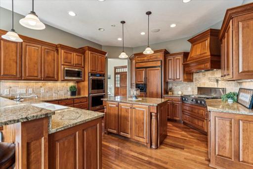 Kitchen features granite countertops, tile backsplash, and large center island. Note the cabinet front refrigerator.