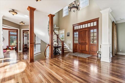 Greet your Guests in style in the Gracious Foyer featuring Elegant Curved Staircase, gleaming hardwood floors, and custom front door with transom and sidelight windows.