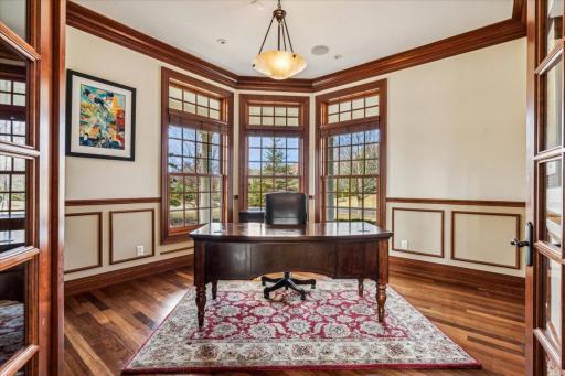 French doors open to this Stunning Executive Office with tons of windows, hardwood flooring, and chandelier.