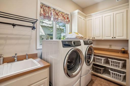 Main level laundry room with built in cabinets and an oversized sink.