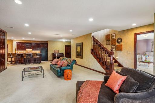 Large lower level family room built for entertaining with full bar and walkout to screened porch, pool, and riverfront.