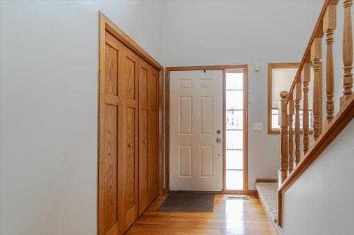 The entry foyer has hardwood floors and a coat closet with solid-panel doors. A full-view sidelight lets natural light in.