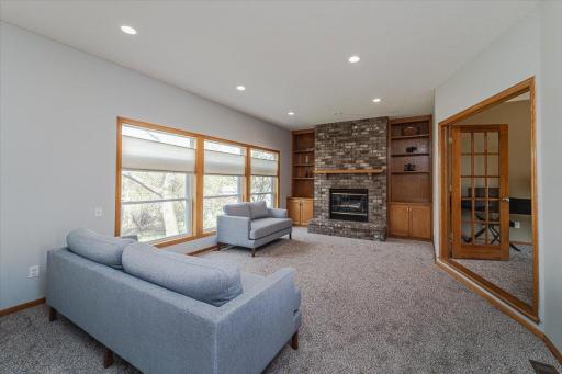 The sunken family room features a wall of windows and BRAND NEW carpet, as well as a wood-burning fireplace with brick surround flanked by built-ins.