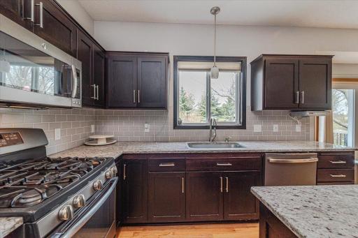 Granite countertops, a subway tile backsplash, and stainless appliances dress up the space. A farmhouse sink lies just beneath the window. The lighting in the kitchen is new.