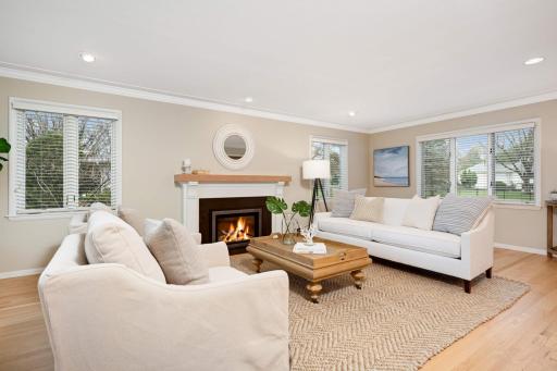 The spacious living room features a gas fireplace with new custom mantle, crown molding and refinished hardwood floors.