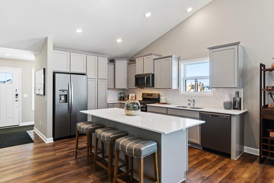 (Photo of a decorated model, actual homes finishes will vary) This spacious kitchen features a large center island, quartz countertops, LVP floors, stainless appliances and more!
