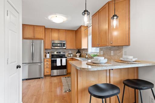 Roomy kitchen with maple cabinets, breakfast bar, granite countertops and stainless steel appliances.