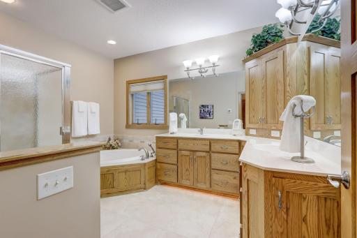 Luxurious spa-like private bathroom featuring dual sinks, a soaking tub, walk-in shower stall, and heated tiled floors.