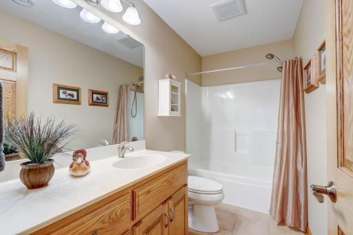 Shared full bathroom with tub/shower combo and tile floors.