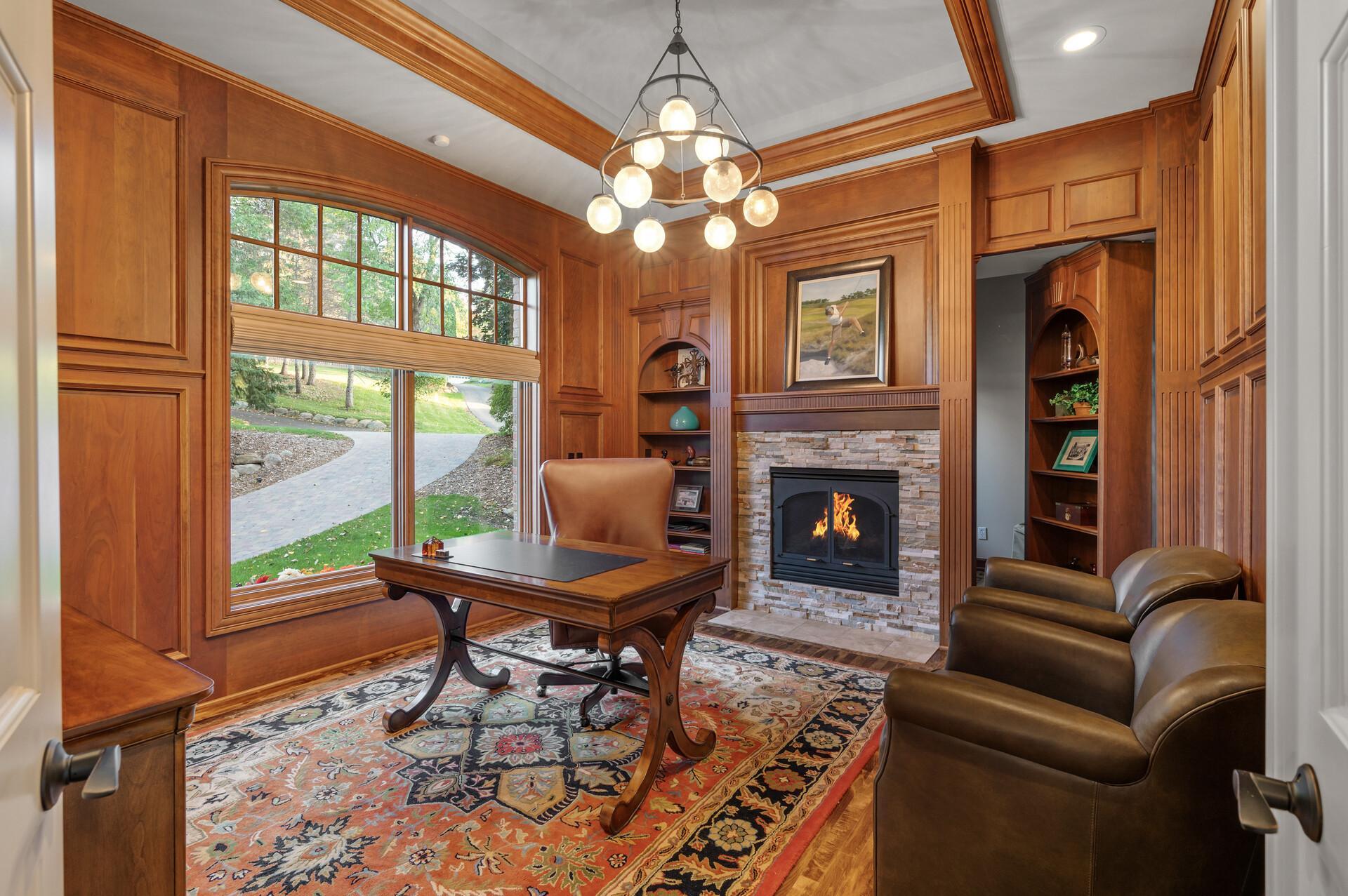 For those who require a dedicated workspace, the main level office is a masterpiece of design, featuring floor-to-ceiling wood paneling, a charming gas fireplace with a stone surround, and a hidden bookshelf door that leads to a roomy storage closet.
