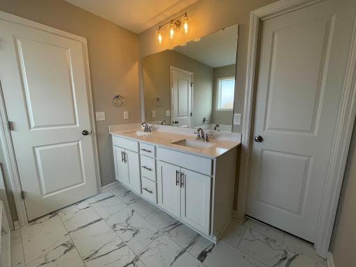 Deluxe primary bath features a double sink vanity, quartz countertops, and LVT flooring.