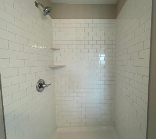 Deluxe primary shower highlights include a subway tile surround with a fiberglass base.