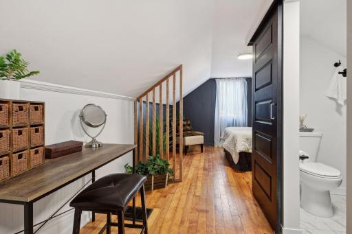 The whole upstairs is your suite but with cleverly defined spaces. Here, a simple wood feature divides the bedroom space from the vanity, desk, or dressing space across from your new 3/4 bath