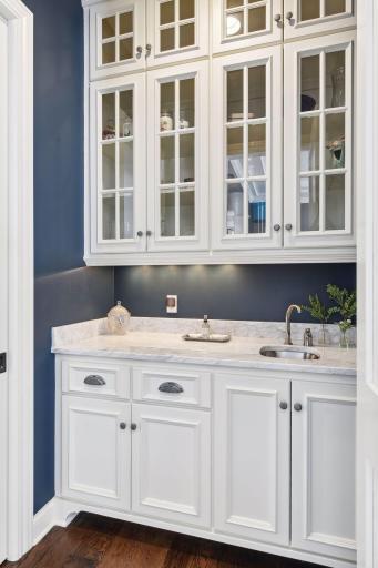 Desired butler's pantry with prep sink, accent light in glass cabinets, & marble countertops.
